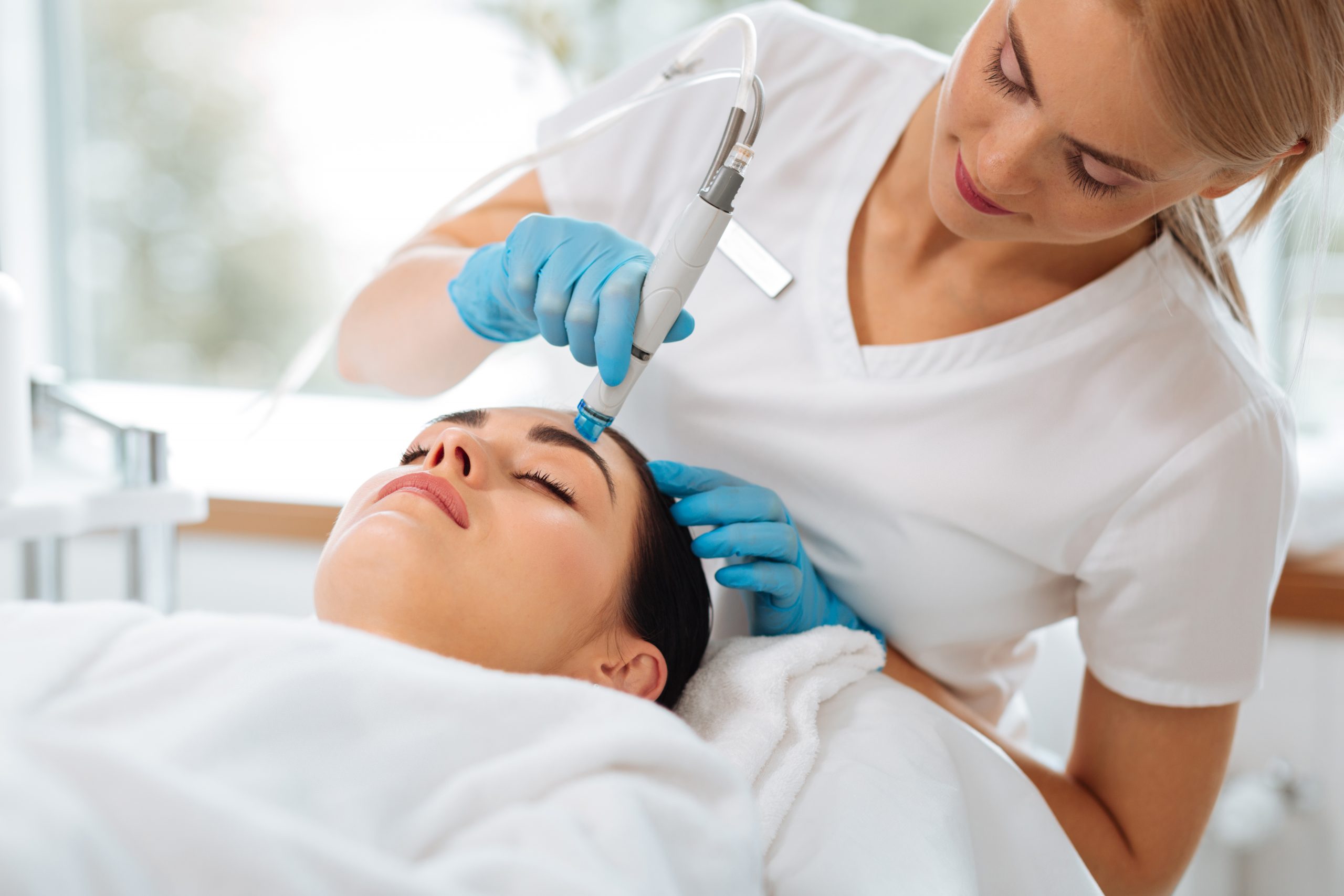 Smart nice cosmetologist looking at the clients face